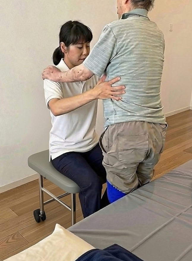 療法士が患者様の姿勢をサポートしながら施術を行っている様子